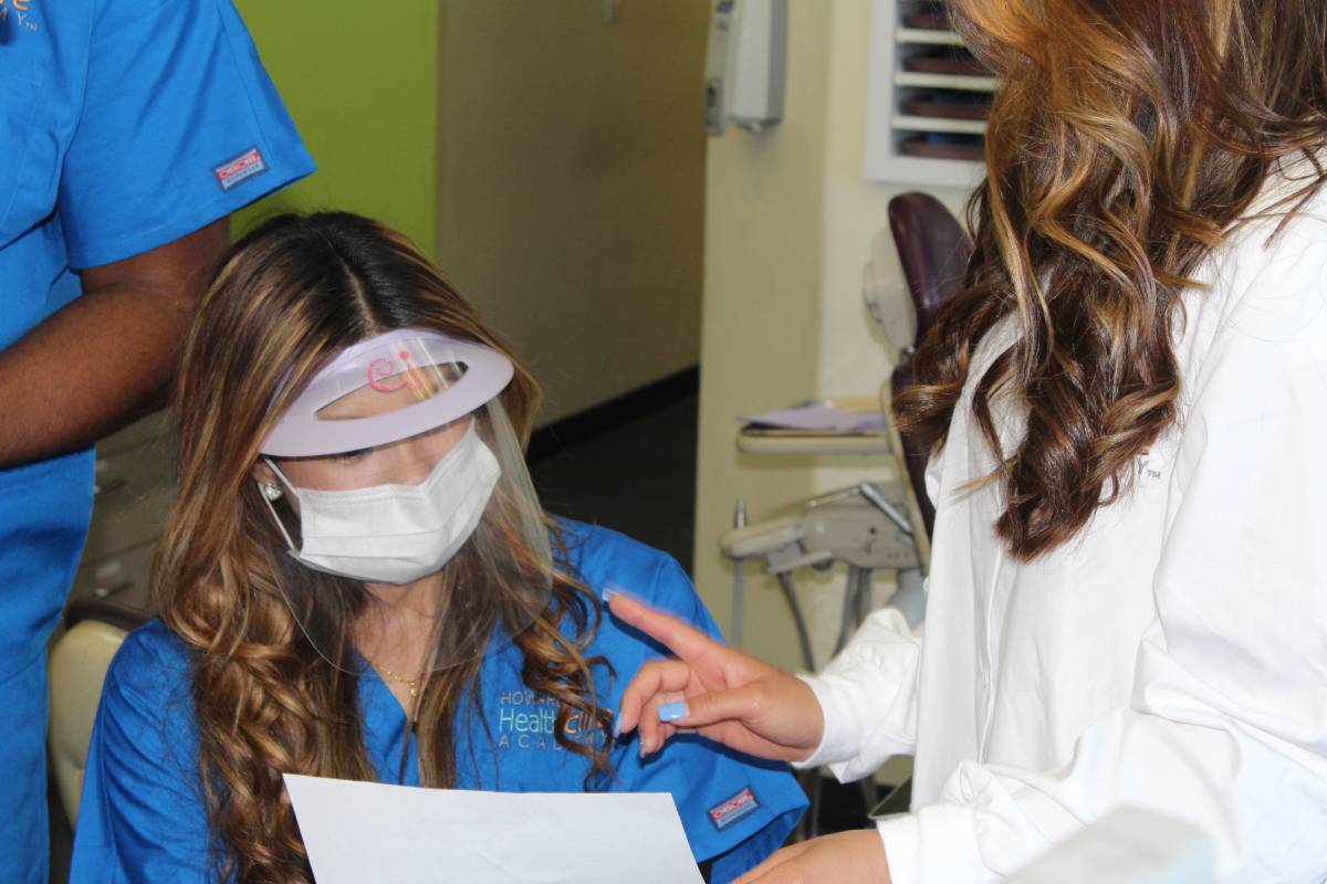 Dental Assistant Trainee Wearing Face Mask Working with Instructor in Classroom Setting