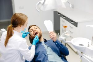 A man receiving treatment from a female dental assistant